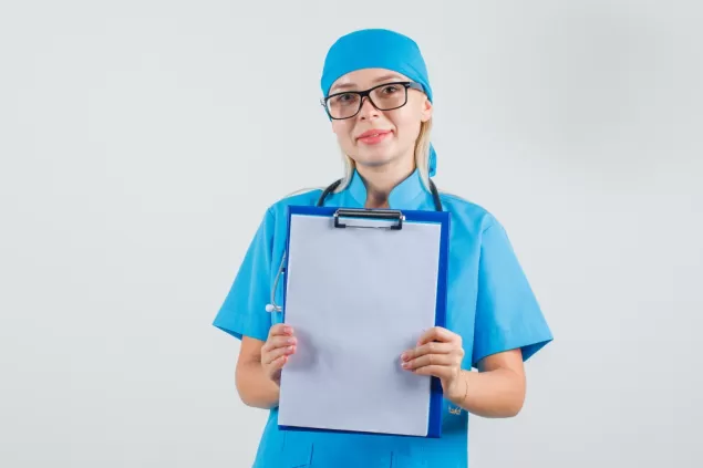 kobieta lekarz trzymajac schowek w niebieskim mundurze okulary i wesoly wygladajacy