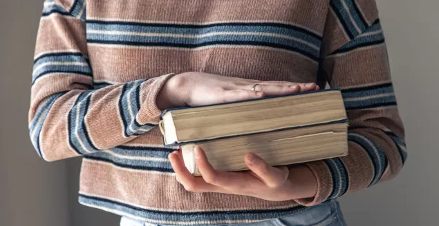 mloda studentka z ksiazkami w reku w pokoju