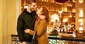 szczesliwa para stoi w objeciach wieczorem na ulicy w swiatecznych swiatlach