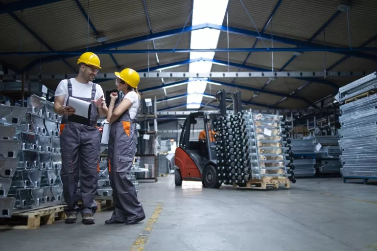 factory workers standing industrial warehouse discussing about production